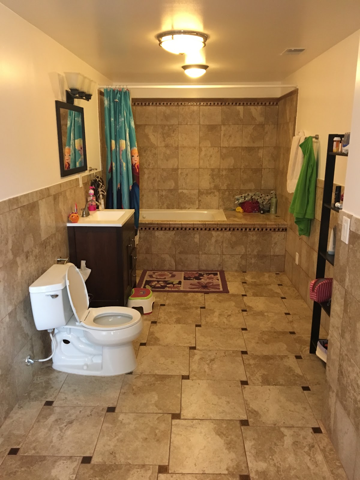 A finished bathroom with tiled tub surround and tiled floor