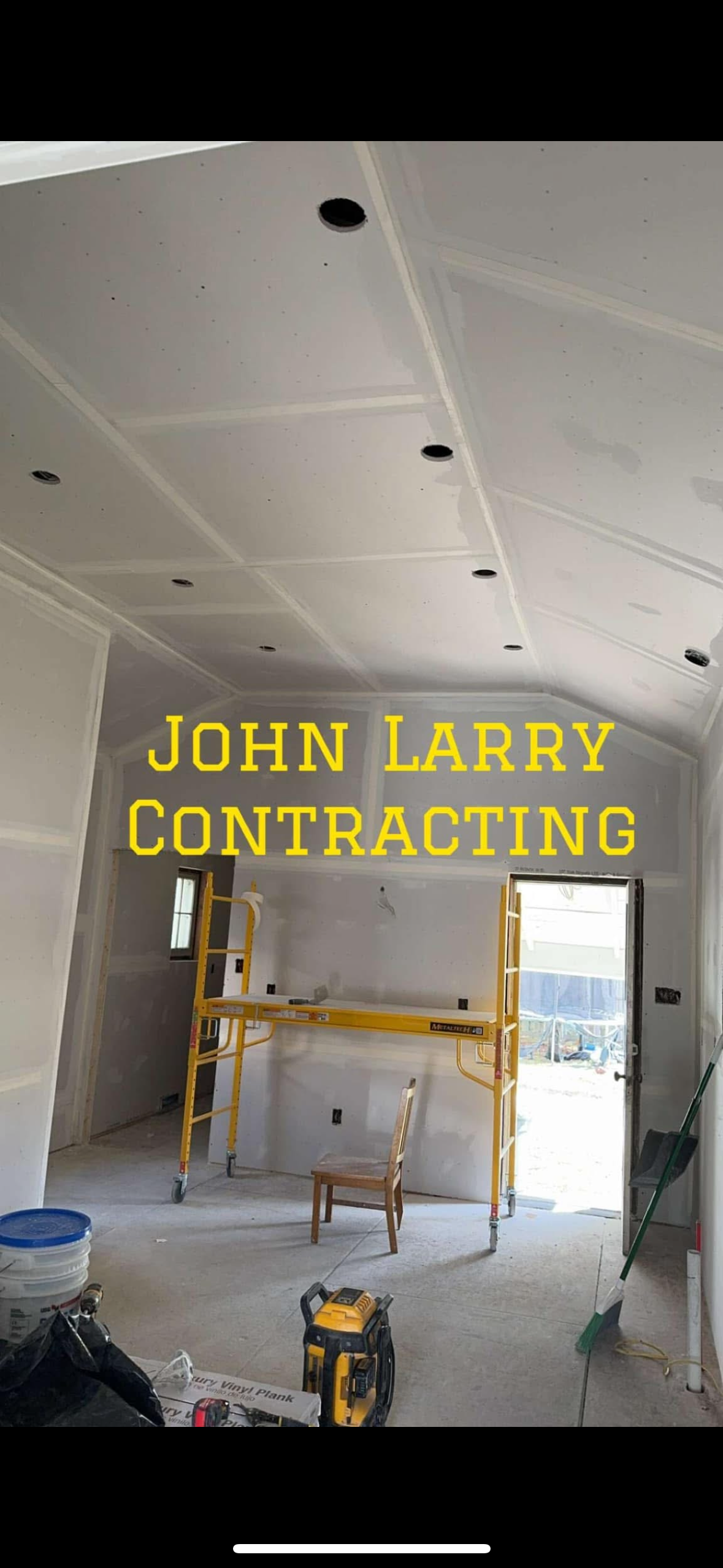 A room mid-renovation with new drywall installed, ceiling recessed lights, and scaffolding, branded with the John Larry Contracting name