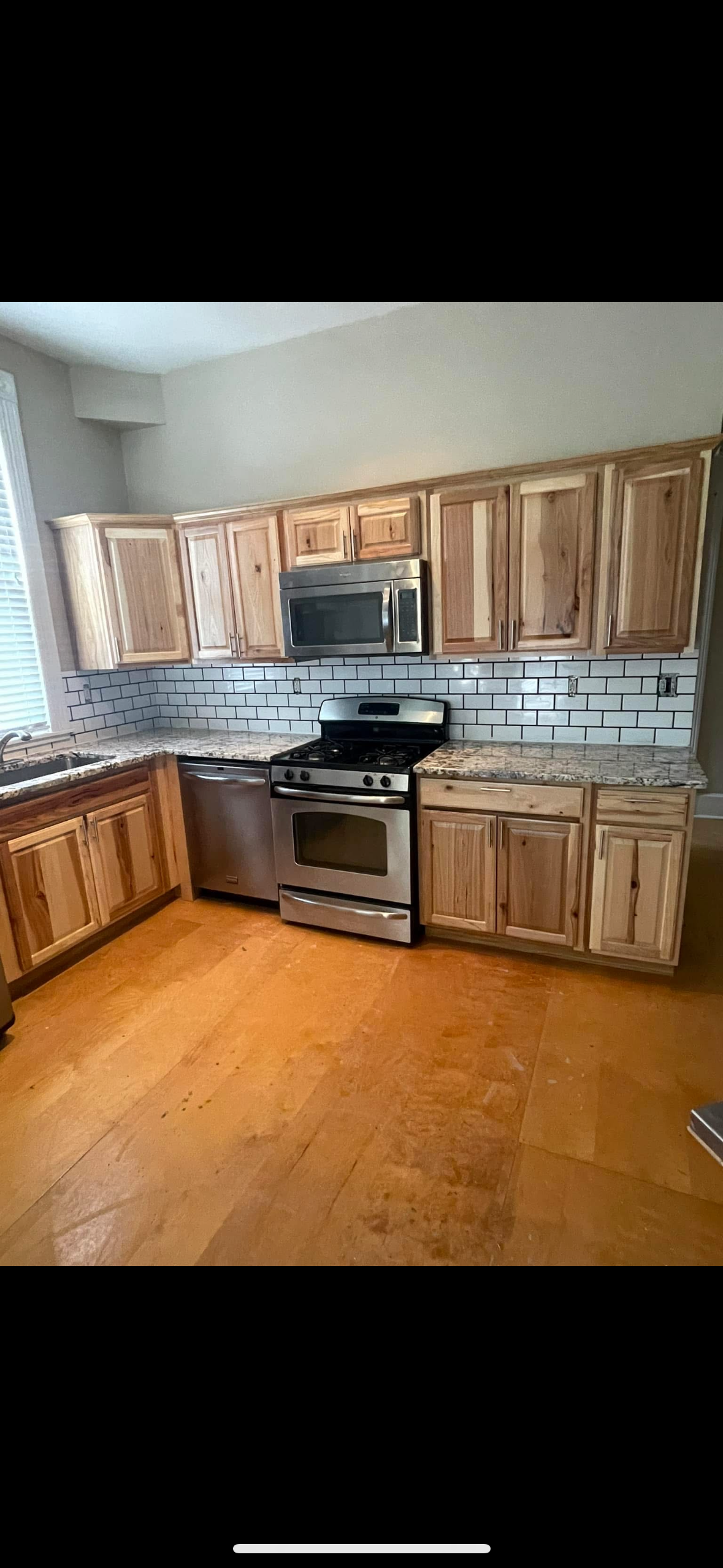 A finished kitchen remodel with hickory cabinets, subway tile backsplash, granite counters, and new stainless steel appliances
